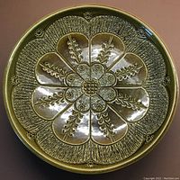 Top view of pottery plate showing detailed floral design and textured patterns in warm glaze colors.