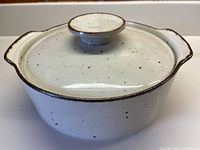 Front angled view of J&G Meakin cream casserole dish with lid showing cinnamon speckled pattern and rim.