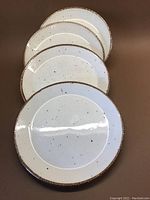 Four round dessert plates with cream background and cinnamon colored rim, showing the overall set layout.