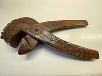 Side view of the hand carved wooden nutcracker showing the entire tool and the decorative carvings on the handle and jaw.