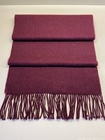 Folded burgundy alpaca scarf showing full length and fringe end.