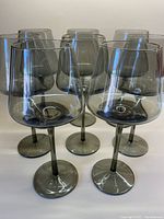 Group of 8 smoky grey tall wine glasses showing their overall shape and color
