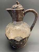 Front angled view showing repousse silver collar, handle and etched crystal body