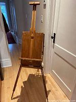 Assembled easel standing on hardwood floor, showing full height and legs extended