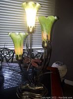 Full view of the 3-light tulip lamp with green glass shades and metal base with dragonfly decoration.