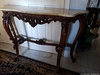 Front view of the sofa table showing carved wood frame and marble top.