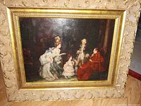 Frontal image of the oil on board painting showing a scene with elegantly dressed 18th-century style figures, set in a detailed gold gilt wooden frame.