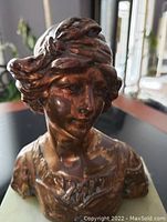 Front close-up view of the bronze female bust statue showing detailed facial features and hair.