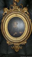Front view of the oval portrait painting in ornate plaster frame.
