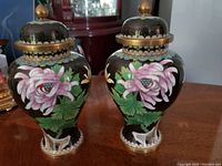 Pair of antique cloisonné urns with floral design and lids, shown side by side.