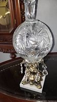 Full view of the vintage cut crystal bowl on the ornate brass base with hanging crystal prisms and marble footed platform