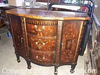 Front view of vintage marquetry wood credenza with three curved drawers and flared side doors closed, ornate brass hardware, wood veneer panels, top surface visible