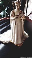 Full front view of the white and gold Queen Elizabeth II figurine standing on square base