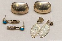 Overview of all three pairs of silver earrings on a neutral surface, showing their shape and relative size.