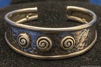 Front view showing hammered texture and three spiral silver accents on the cuff bangle.