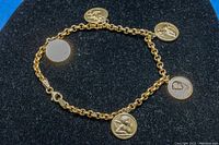 Full view of 7-inch gold-toned charm bracelet with five religious medallions on black background.