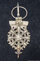 Full view of antique Berber fibula pendant showing circular ring, pin, and detailed radiating pattern with central dome.