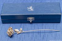 Sterling silver rose placed next to the original blue box with lion emblem on top.