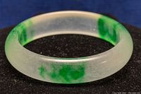 Close-up image of the jade bangle highlighting the mixture of translucent white and green jade with smooth polished surface.