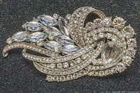 Close up photo showing the front view of the vintage brooch with clear crystals of various cuts and sizes forming a feather-like pattern.