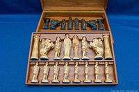 Open wooden case showing both light and dark chess pieces arranged in molded slots across two tiers
