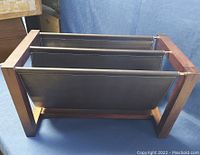 Front and side view showing wooden frame and two black sling compartments for magazines.