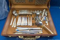 Opened case showing layout of flatware items including forks, spoons, knives and serving utensils.