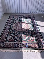 Full view of the 5x8 rug showing green background and floral patterned medallion in center with border and fringe edges.
