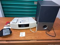 Full lot view showing Bose Wave Radio/CD, remote, Altec Lansing speaker, and iPhone armbands on a wooden table.