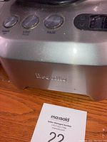 Close-up of Breville food processor metal base with power and control buttons and brand name on front.