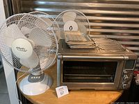 Overview showing Breville oven, three tabletop fans, trays and wire rack on countertop
