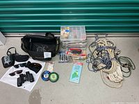 Full view of lot contents including tackle boxes, ropes, cords, binoculars, sunglasses, fishing maps, and carrying bag.