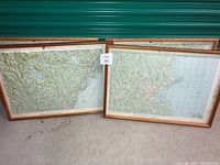 Four wooden-framed topographical maps leaned against a green background. Three maps depict Maine areas and one Boston.