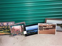 Five framed oil paintings from the lot arranged side-by-side showing diverse scenic themes including mountains, horses, and boats.