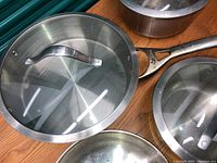 Close-up photo of one Calphalon stainless steel saucepan with glass lid showing metal handle and brushed steel finish.