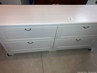 Front view of the white dresser showing all four drawers with metal handles.