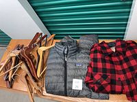 Photo showing men's Patagonia puffer jacket, L.L. Bean flannel jacket, and wooden hangers on a table.