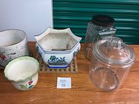 Overview of two glass jars and three ceramic planters on wooden surface