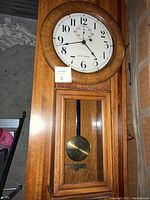 Full-length front view showing round dial and lower pendulum door