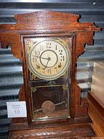 Full view of the Ingraham Mission Oak mantel clock, showing the wooden case, dial, and pendulum behind glass.