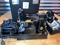Singer sewing machine with foot pedal and accessory tray on wooden table