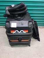 Front and top view of the Mi-T-M XL wet/dry vacuum showing hose coiled on top and power switch.