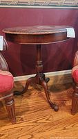 Round tabletop and entire end table showing the classical carved design and pedestal base.