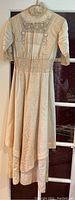 Full length of antique Victorian wedding dress showing lace and silk, long sleeves, high collar, and flowing skirt.