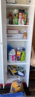 White shelving cabinet containing assorted cleaning supplies, aerosol cans, spray bottles, paint brushes and other painting consumables