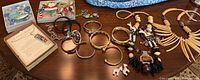 Photo showing assorted costume jewelry laid out on a wooden table including bangles, cuffs, necklaces, and holiday-themed pieces.