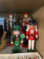 Four nutcrackers displayed including two kings with scepters, a green leprechaun nutcracker holding a shamrock, and a soldier nutcracker with white pants.