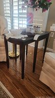 Pair of wooden nesting side tables positioned side by side, top surfaces holding decorative items not included in the lot