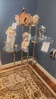 Full view of 5-tier metal and glass plant stand holding several decorative items