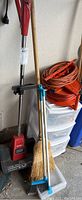 Full view showing Toro power shovel alongside two brooms and plastic drawer unit.
